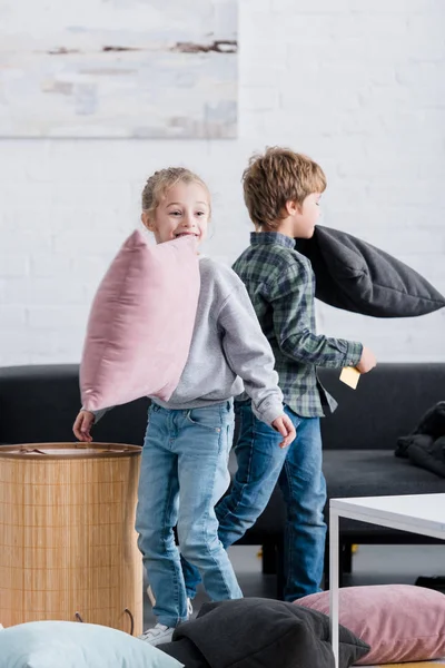 Irmãos adoráveis lutando com travesseiros e se divertindo em casa — Fotografia de Stock