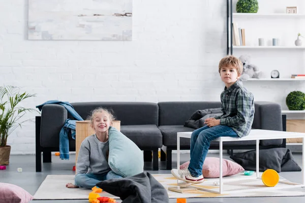 Lindo hermano y hermana jugando juntos y mirando a la cámara en casa - foto de stock