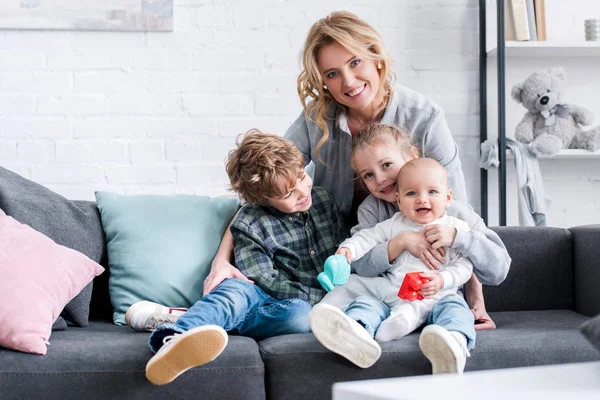 Hermosa madre feliz con tres niños adorables sonriendo a la cámara - foto de stock