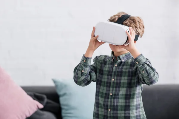 Очаровательный маленький мальчик, использующий гарнитуру виртуальной реальности дома — стоковое фото