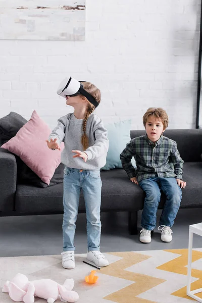 Beautiful brother and sister using virtual reality headset at home — Stock Photo