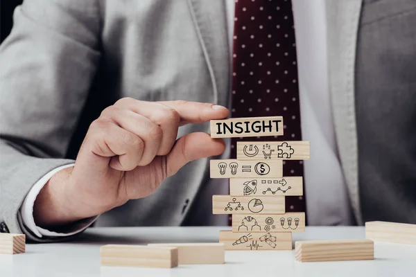 Cropped view of man holding brick with word 'insight' over wooden blocks with icons — Stock Photo