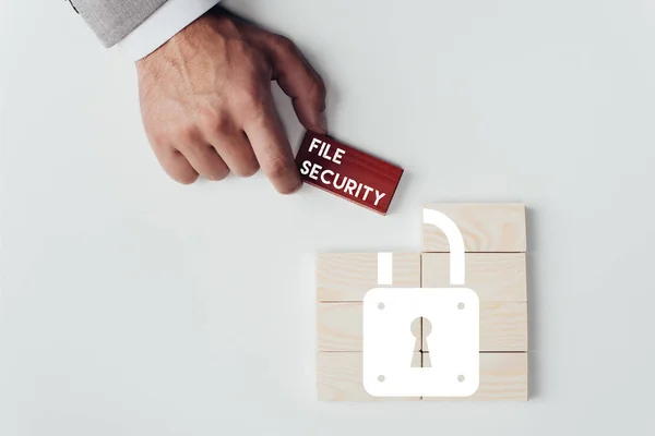 Partial view of man holding brick with 'file security' lettering over wooden blocks with lock icon isolated on white — Stock Photo