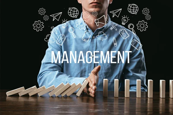 Cropped view of man preventing wooden blocks from falling with word 'management' and icons on foreground — Stock Photo