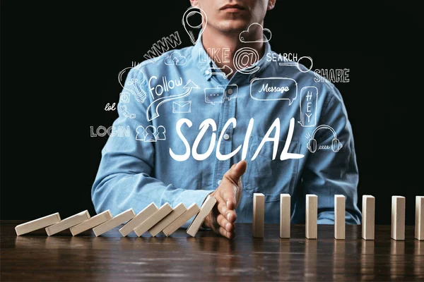 Vista cortada do homem impedindo blocos de madeira de cair com a palavra 'social' e ícones em primeiro plano — Fotografia de Stock