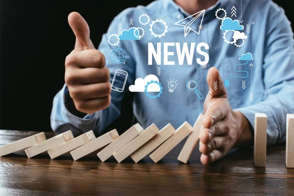 Partial view of man showing thumb up sign while preventing wooden blocks from falling with word and icons on foreground — Stock Photo