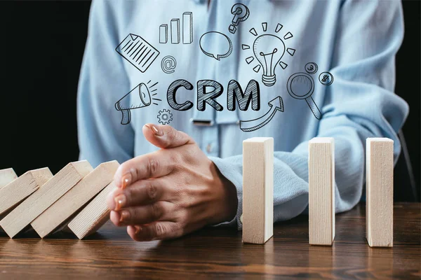 Close up view of woman preventing wooden blocks from falling with word 'crm' and icons on foreground — Stock Photo