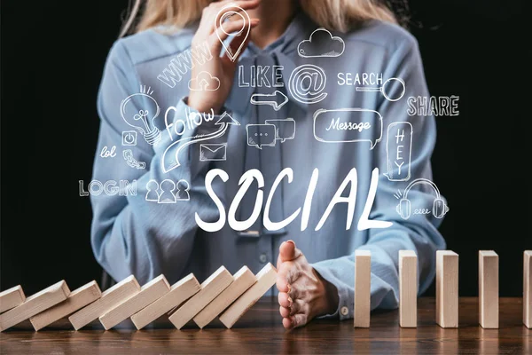 Cropped view of woman preventing wooden blocks from falling with word 'social' and icons on foreground — Stock Photo