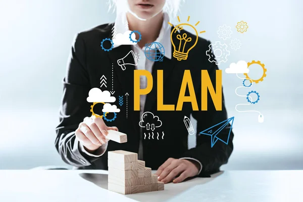 Cropped view of woman building career ladder with wooden blocks, icons and 'plan' lettering on foreground — Stock Photo