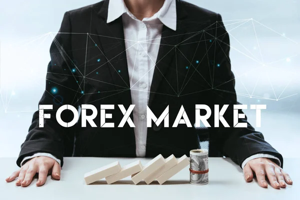 Cropped view of businesswoman with wooden blocks and money roll on table and 'forex market' lettering on foreground — Stock Photo