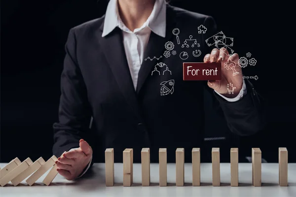 Cropped view of businesswoman holding red brick with 'for rent' words while preventing wooden blocks from falling, icons on foreground — Stock Photo