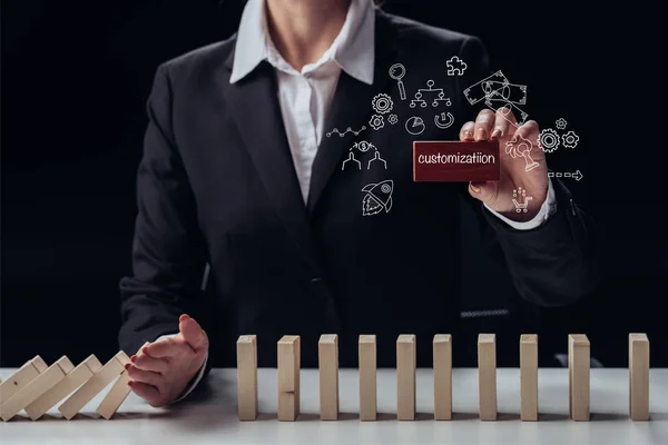 Cropped view of businesswoman holding red brick with 'customization' word while preventing wooden blocks from falling, icons on foreground — Stock Photo