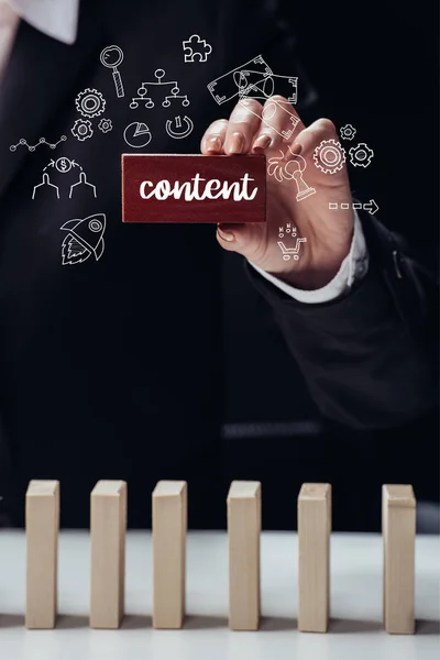 Cropped view of woman holding red wooden brick with word 'content' isolated on black, icons on foreground — Stock Photo