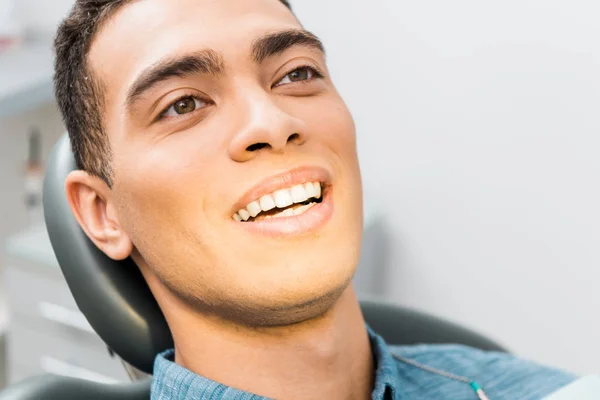 Primer plano de sonriente afroamericano hombre en clínica dental - foto de stock