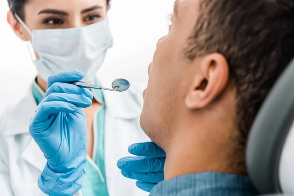 Messa a fuoco selettiva delle mani femminili del dentista in guanti di lattice esaminando paziente afro-americano — Foto stock