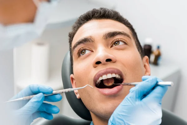 Hombre afroamericano con boca abierta durante chequeo en clínica dental - foto de stock