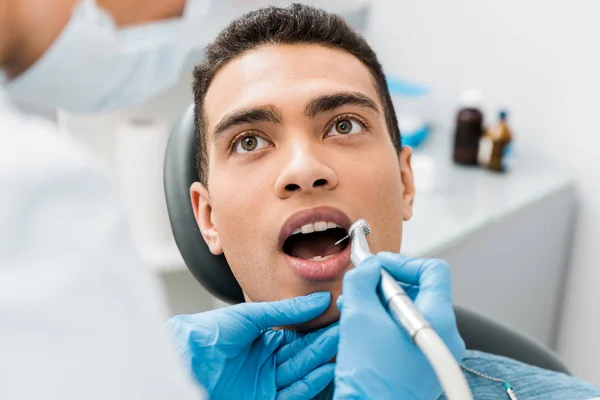 Primer plano de dentista perforación de dientes de hombre afroamericano - foto de stock