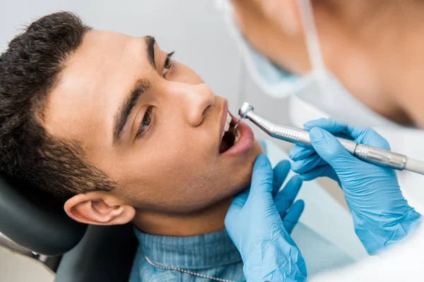 Perto de mãos dentista perfurar dentes de belo paciente afro-americano — Fotografia de Stock