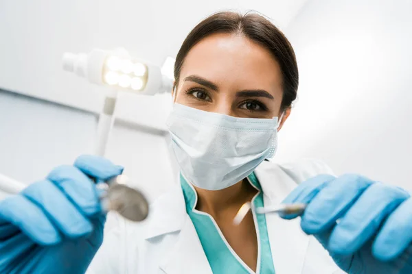 Foco seletivo do dentista feminino na máscara que mantém instumentos em mãos — Fotografia de Stock