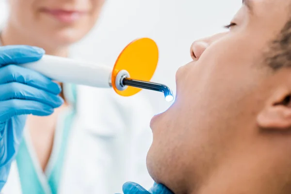 Selective focus of african american man during whitening procedure — Stock Photo