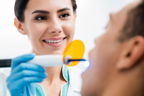 Selective focus of female dentist making bleaching procedure to african american patient — Stock Photo