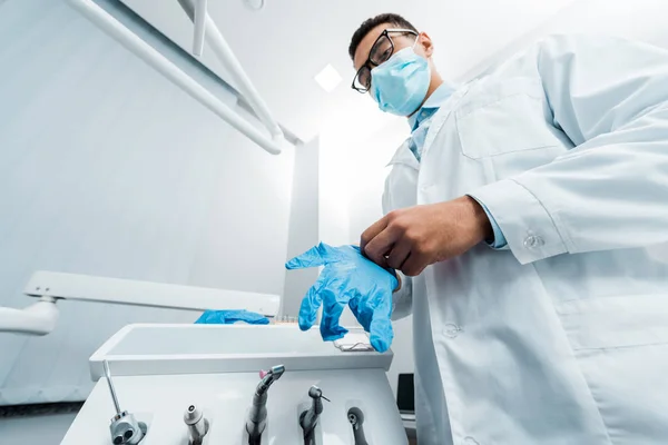 African american dentist in glasses and mask wearing latex glove — Stock Photo
