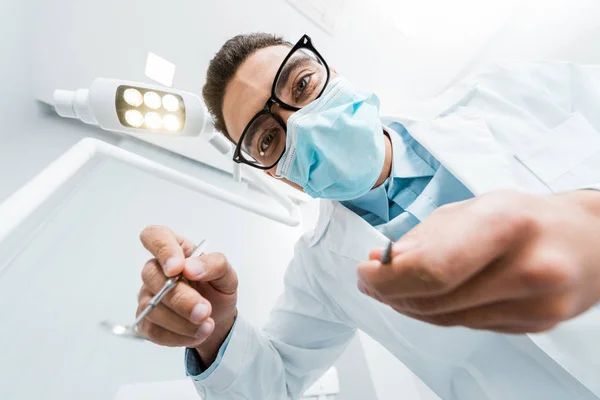 Dental instruments in hands of male dentist in glasses and mask — Stock Photo