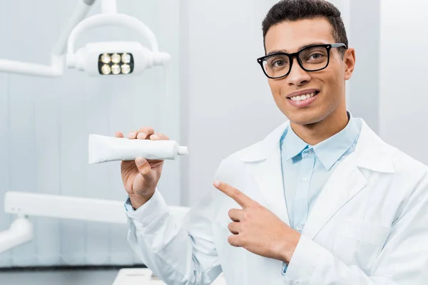 Handsome african american doctor showing toothpaste in dental clinic — Stock Photo