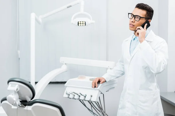 Bonito dentista afro-americano em óculos falando no smartphone — Fotografia de Stock