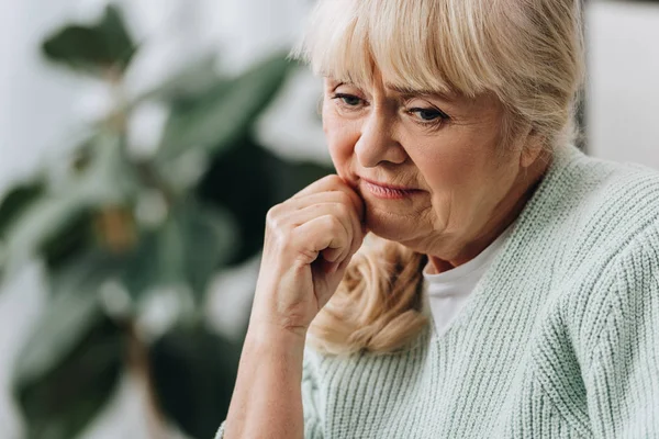 Pensive blonde senior woman in living room — Stock Photo