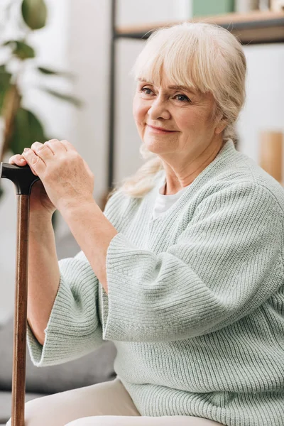 Fröhliche Seniorin lächelt und hält Gehstock in der Hand — Stock Photo