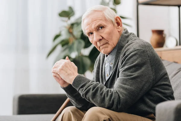 Sad pensioner sitting on sofa in living room — Stock Photo