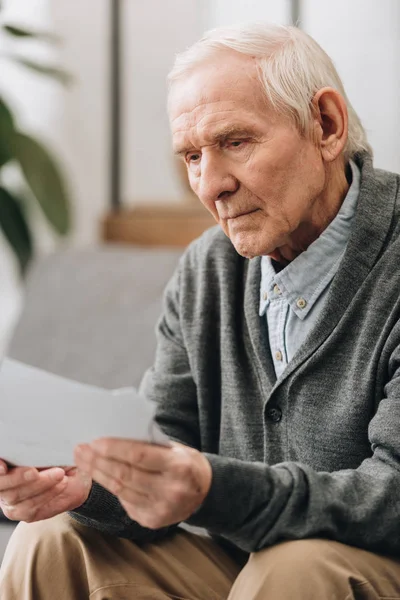 Retired man with grey hair looking at photos at home — Stock Photo