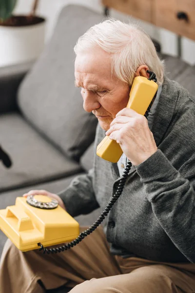 Senior man talking on retro phone at home — Stock Photo