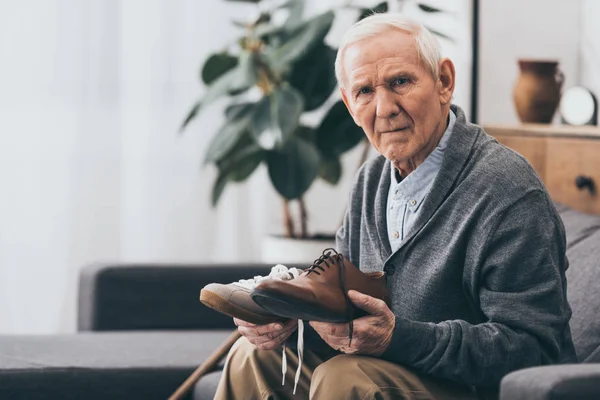 Senior homme tenant des chaussures classiques et modernes dans les mains — Photo de stock