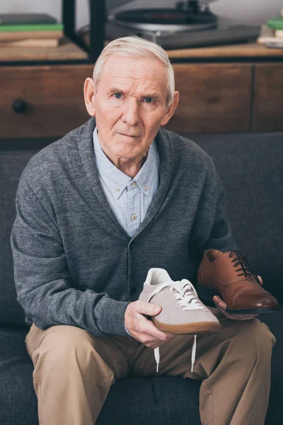 Homem aposentado escolhendo entre sapatos clássicos e modernos — Fotografia de Stock