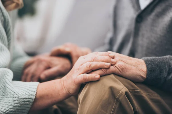 Cropped view of retired couple holding hands — Stock Photo