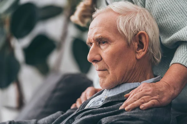Обрізаний вид на пенсійну дружину обіймає сумного старшого чоловіка вдома — стокове фото