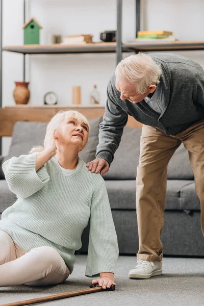 Seniorin sitzt auf dem Boden und betrachtet unterstützenden Rentner — Stockfoto