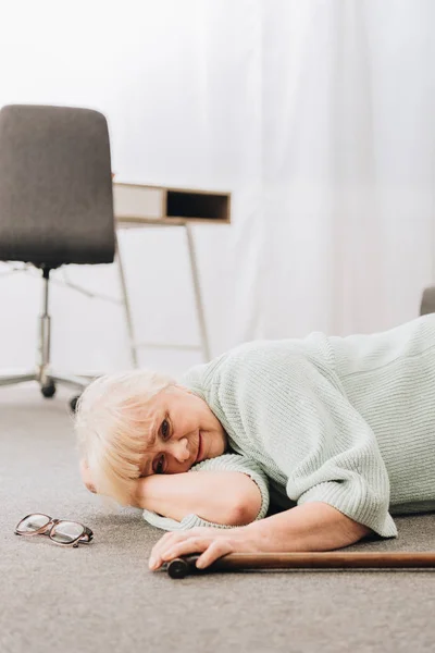 Femme âgée sans défense couchée sur le sol dans le salon — Photo de stock