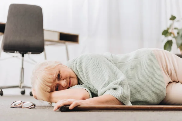 Самотня жінка на пенсії лежить на підлозі у вітальні — стокове фото