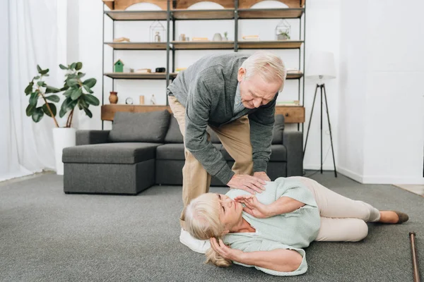 Старші чоловіки допомагають старій жінці, яка впала на підлогу — стокове фото