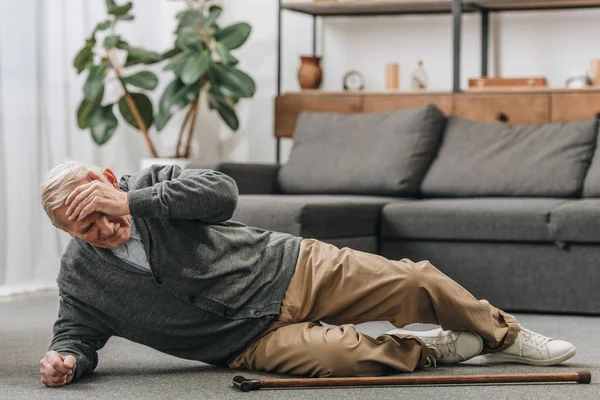 Old men falled down on floor and touching forehead — Stock Photo