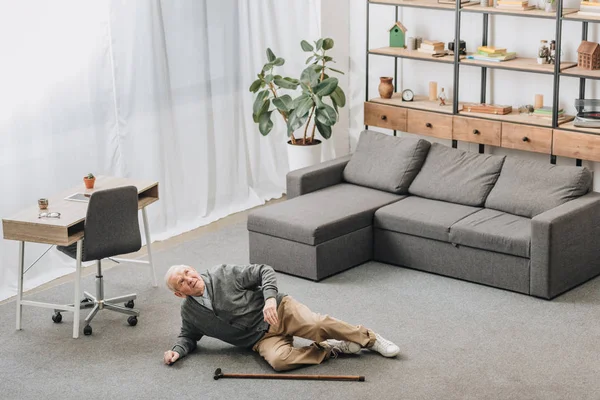 Old man falled down on floor of the room near walking stick — Stock Photo