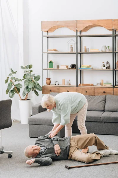Old woman helping husband who falled down on floor — Stock Photo