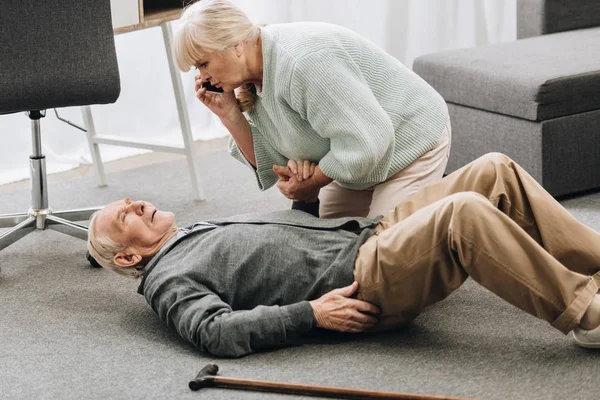 Senior woman looking at husband who falled down with heart attack and dying — Stock Photo