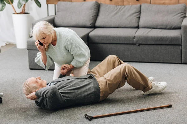 Senior woman holding hand of dying old man with walking stick — Stock Photo