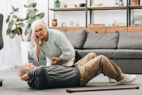 Senior woman holding hand of dying old man with walking stick and looking at camera — Stock Photo