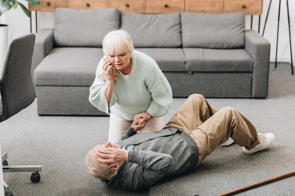 Senior woman helping to husband who falled down on floor — Stock Photo