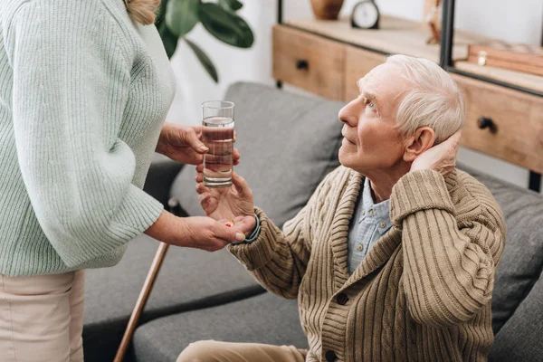 Senior woman helping to old man with walking stick and giving pills — Stock Photo